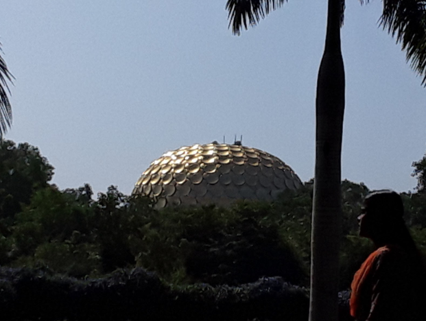 The golden dome of the Matramandir rises over the forest of Auroville