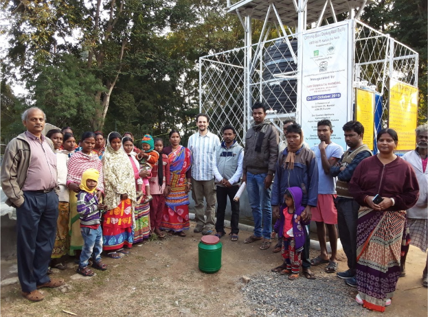 Standing with villagers and DRCSC staff in front of a water purification system whose waste water is feeding a thriving vegetable garden.